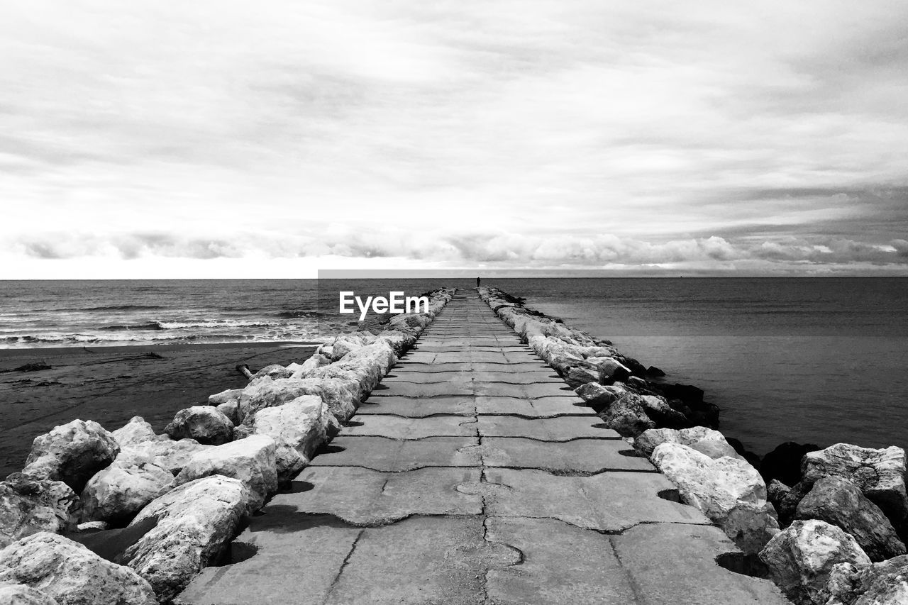 Footpath amidst sea against sky