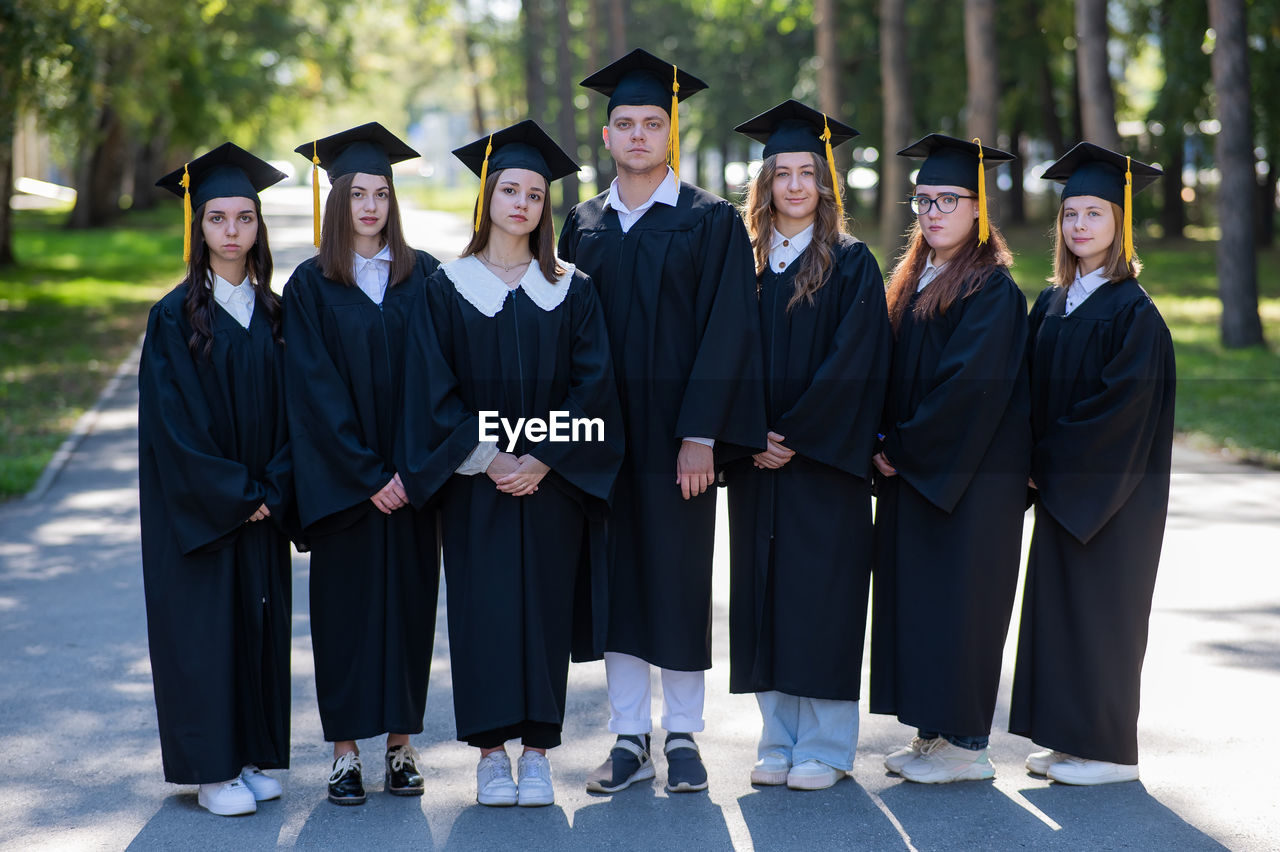 low section of woman wearing graduation gown standing in park