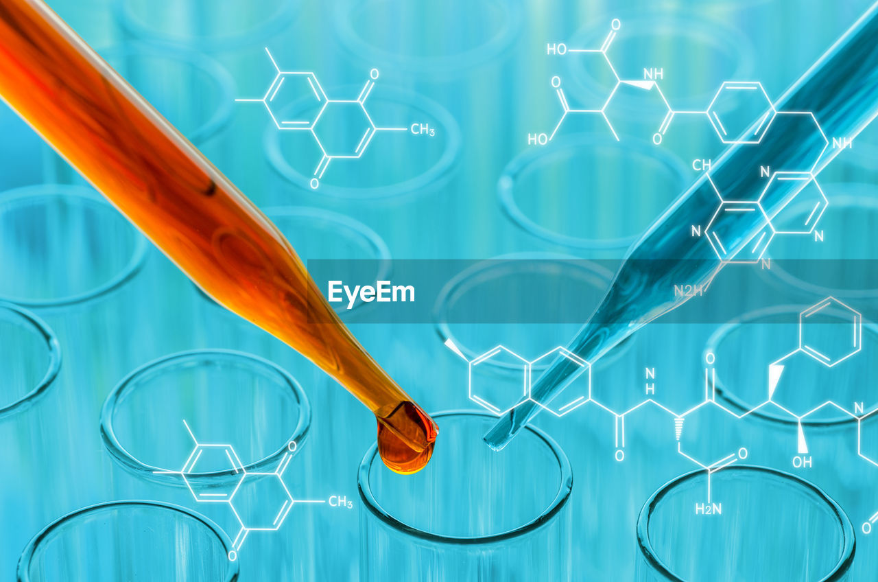 Pipette dripping chemical in test tube at laboratory