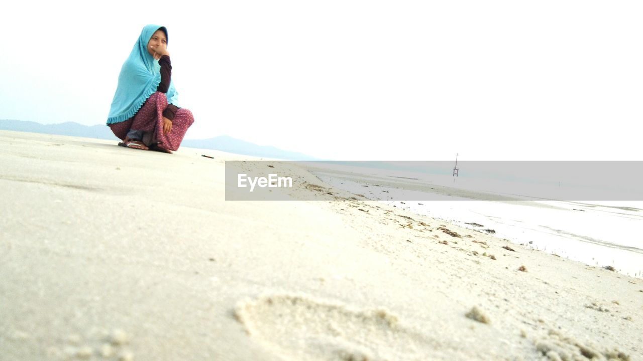 Woman crouching on shore at beach