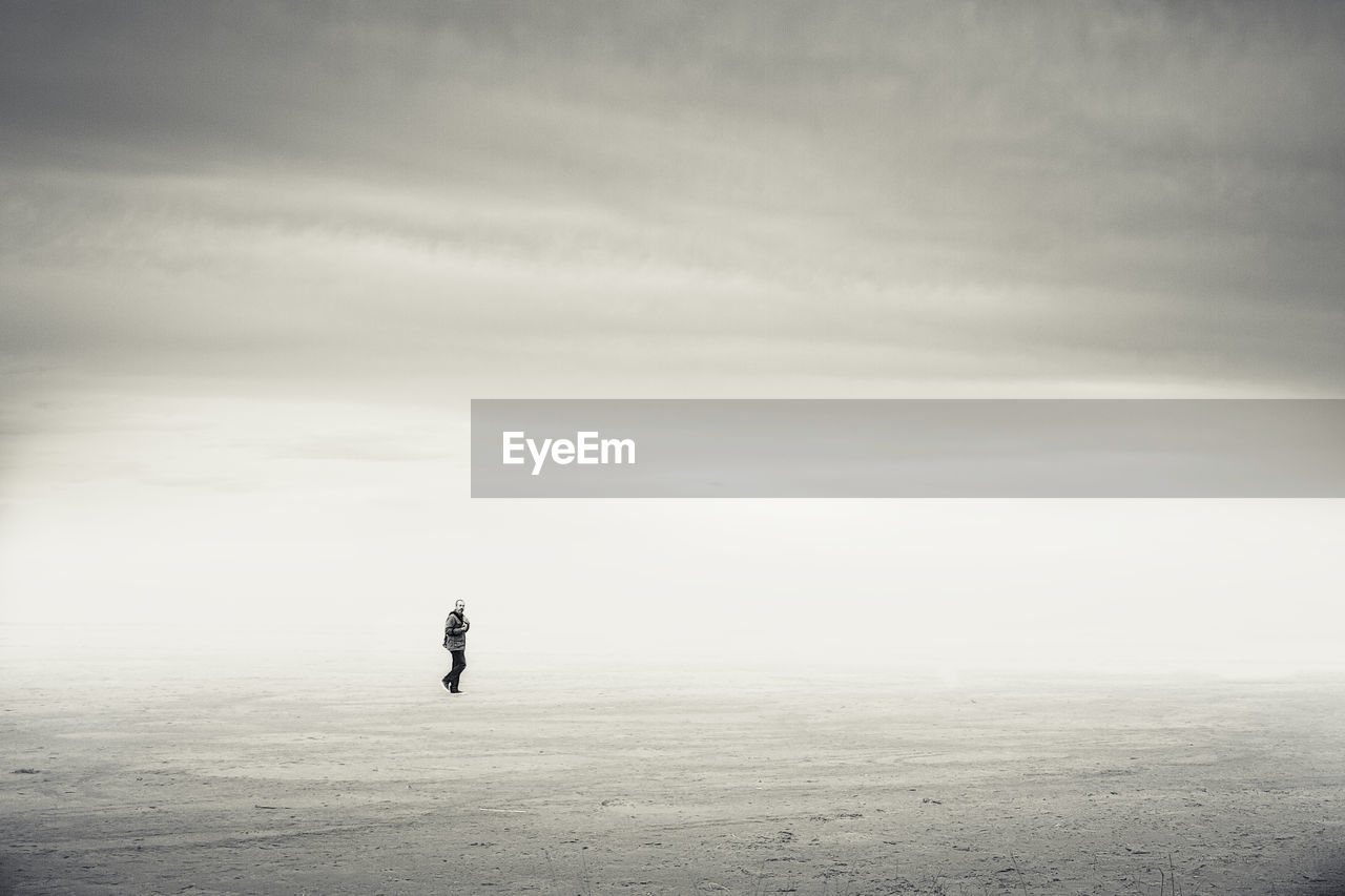 Man walking on beach at ebro delta during foggy weather