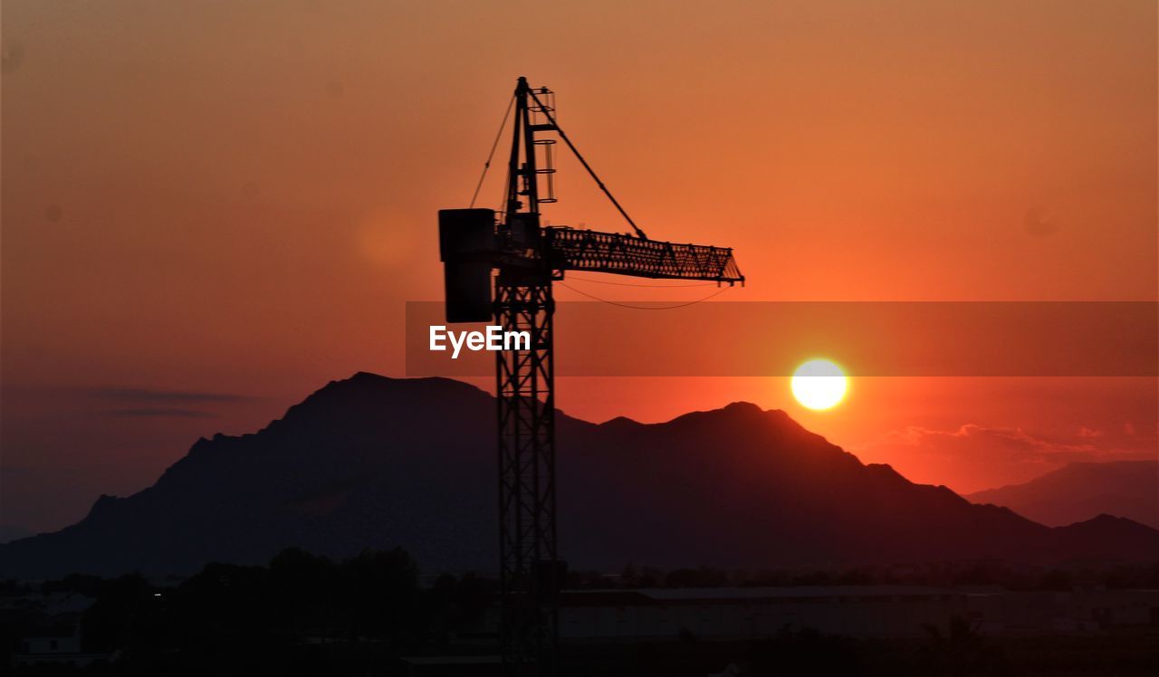 sunrise, sky, afterglow, silhouette, dawn, nature, horizon, orange color, industry, sun, mountain, beauty in nature, machinery, no people, morning, architecture, red sky at morning, crane - construction machinery, environment, technology, scenics - nature, outdoors, landscape, construction industry, business finance and industry, water, dramatic sky, built structure, sunlight, equipment