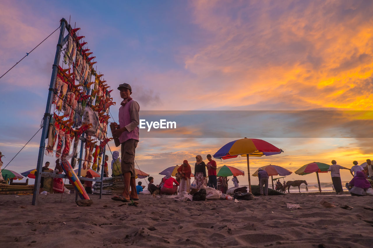 PEOPLE AT BEACH AGAINST SKY