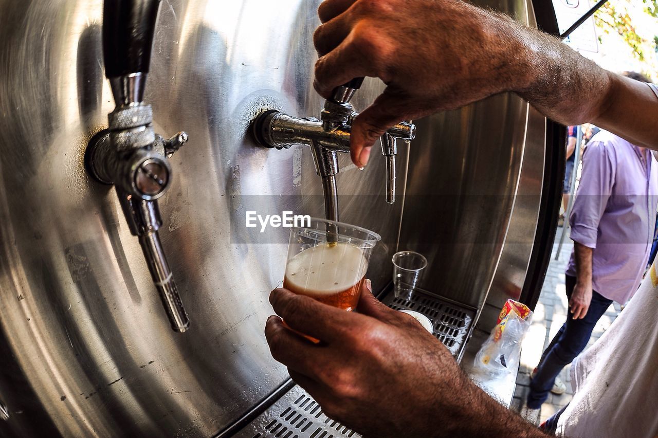 Man pouring beer in disposable glass from tap