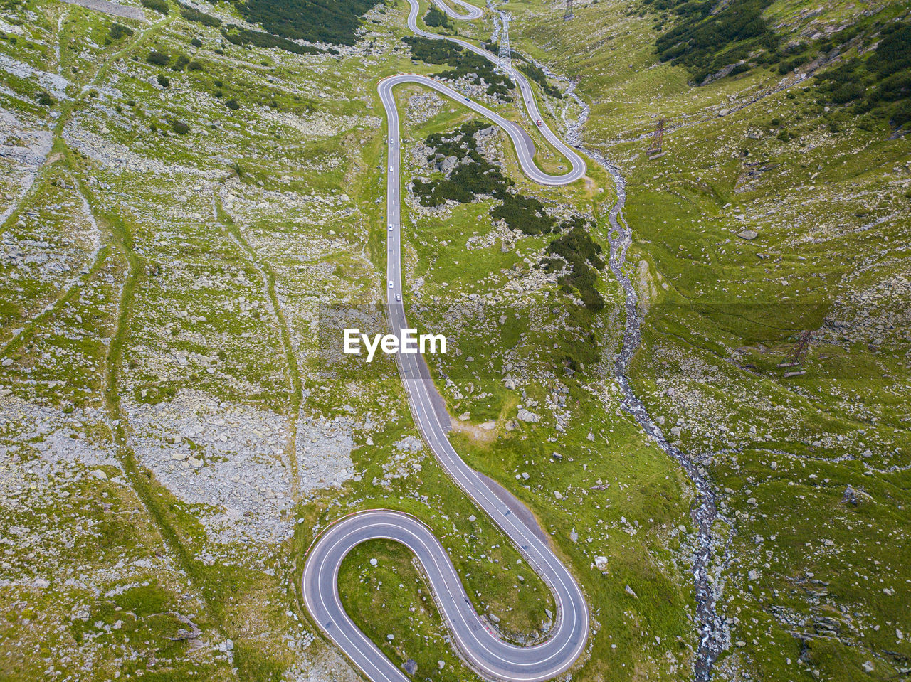 Winding road through the forest, from high mountain pass, in summer time. aerial view by drone