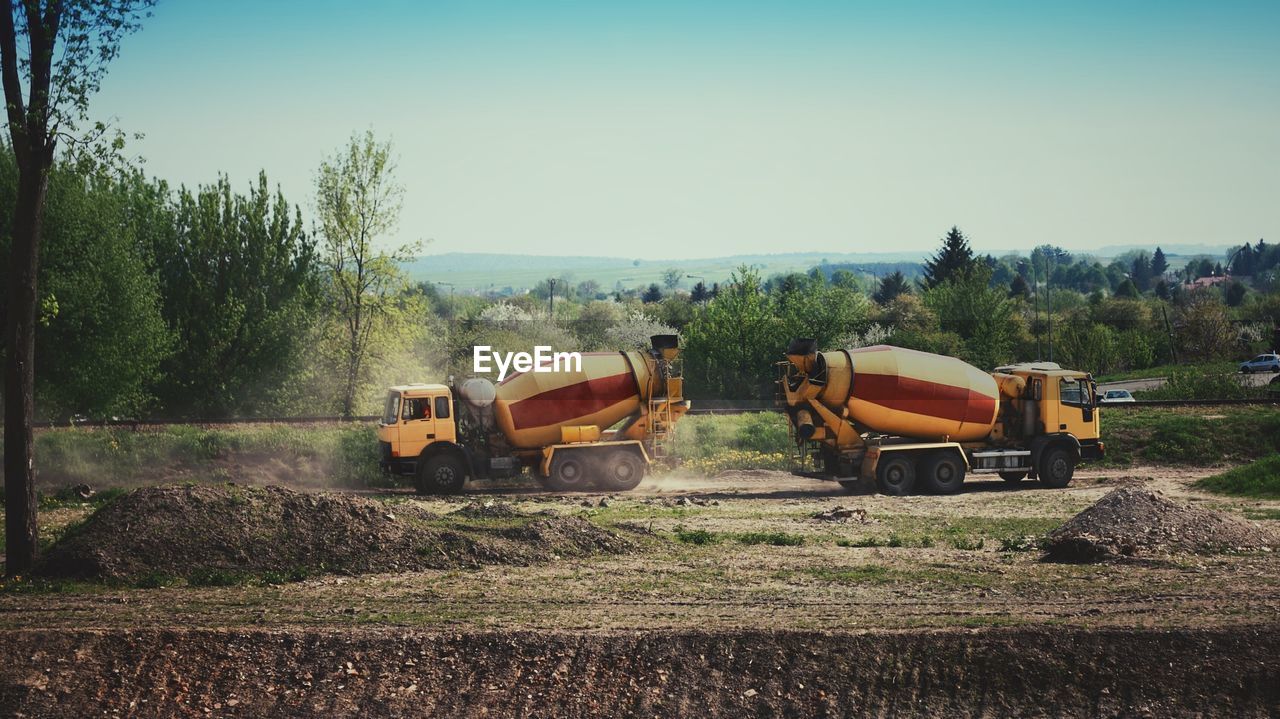 Cement mixer on field against sky