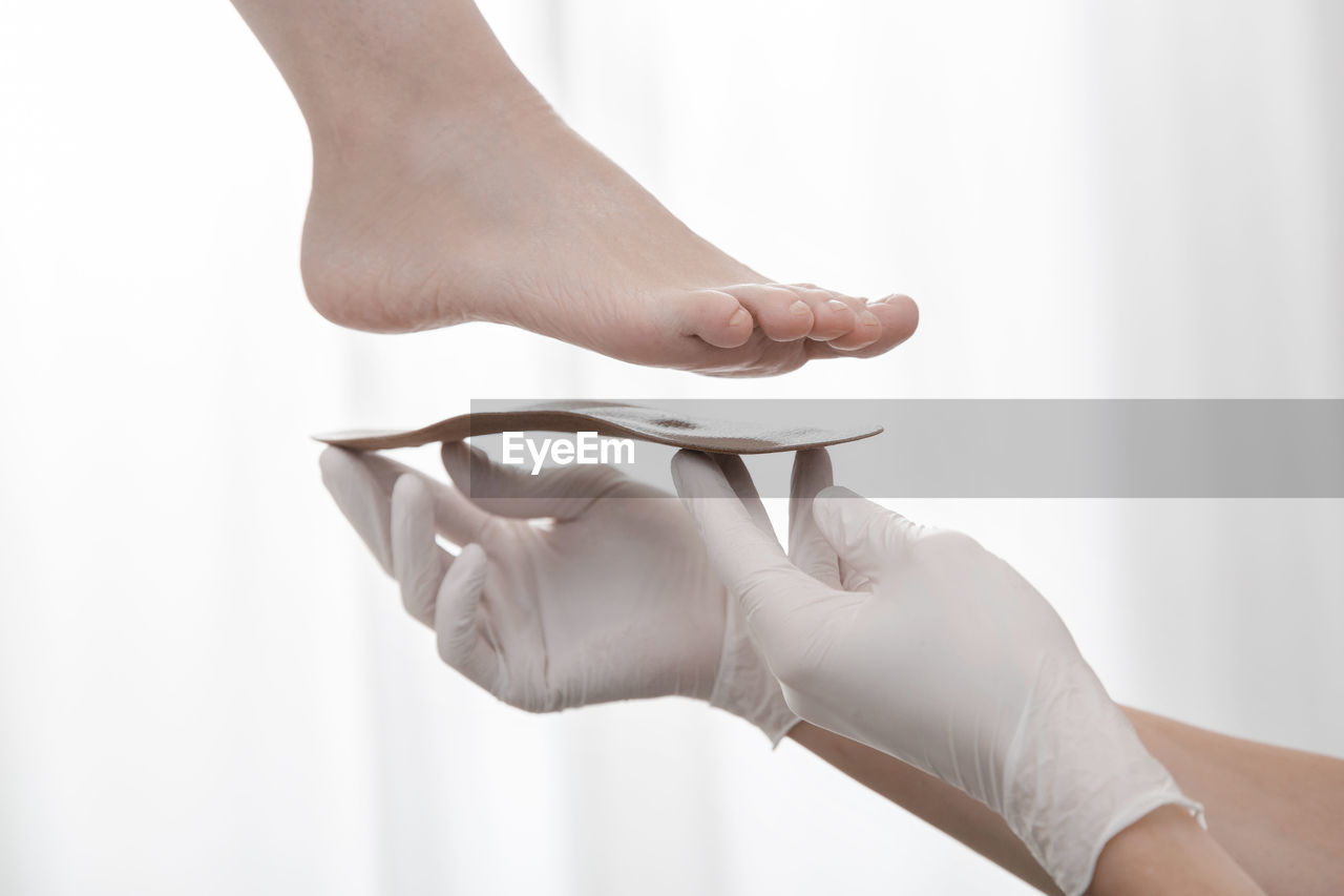 Cropped hand of doctor holding insoles by patient feet