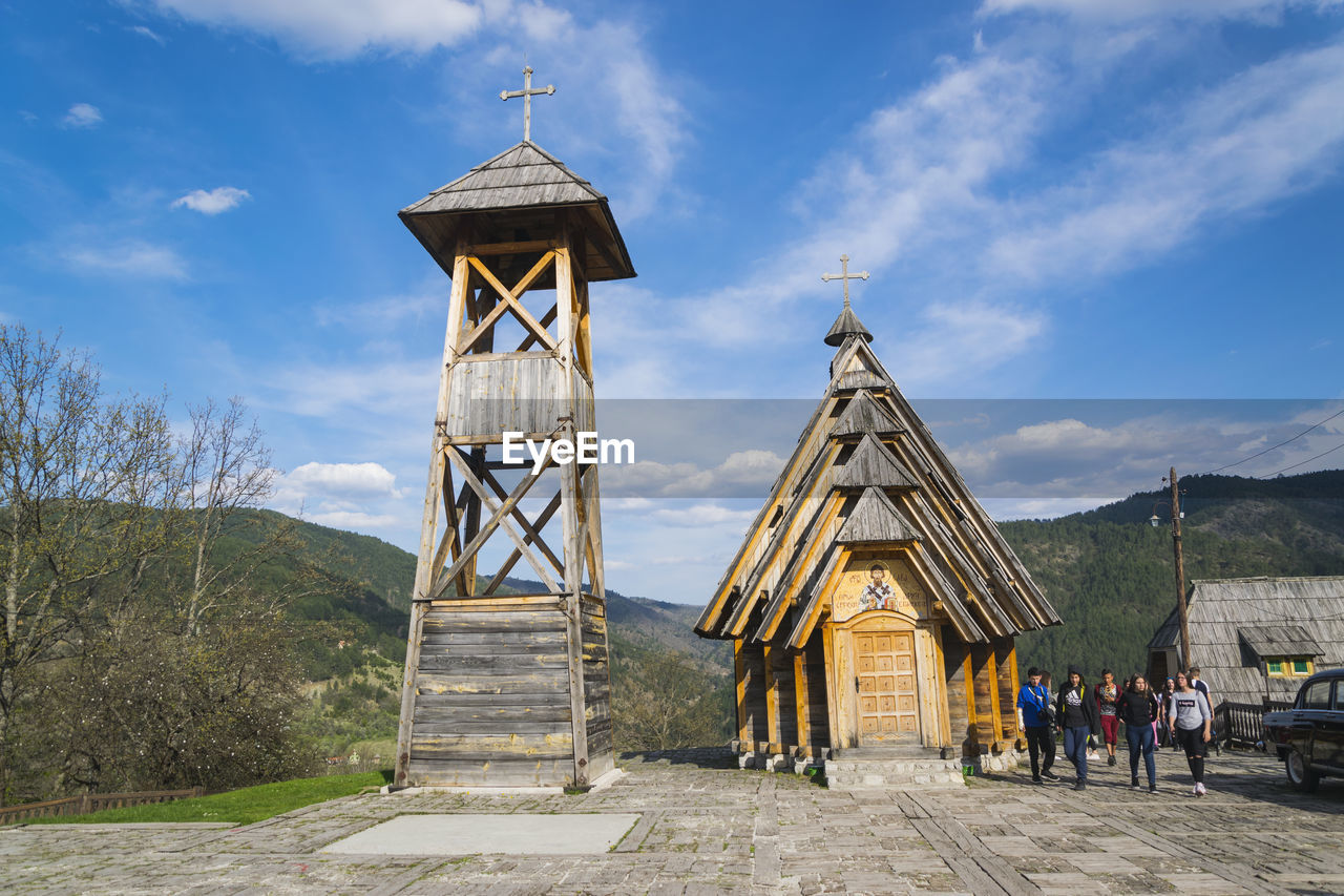 PEOPLE AT TRADITIONAL WINDMILL AGAINST SKY