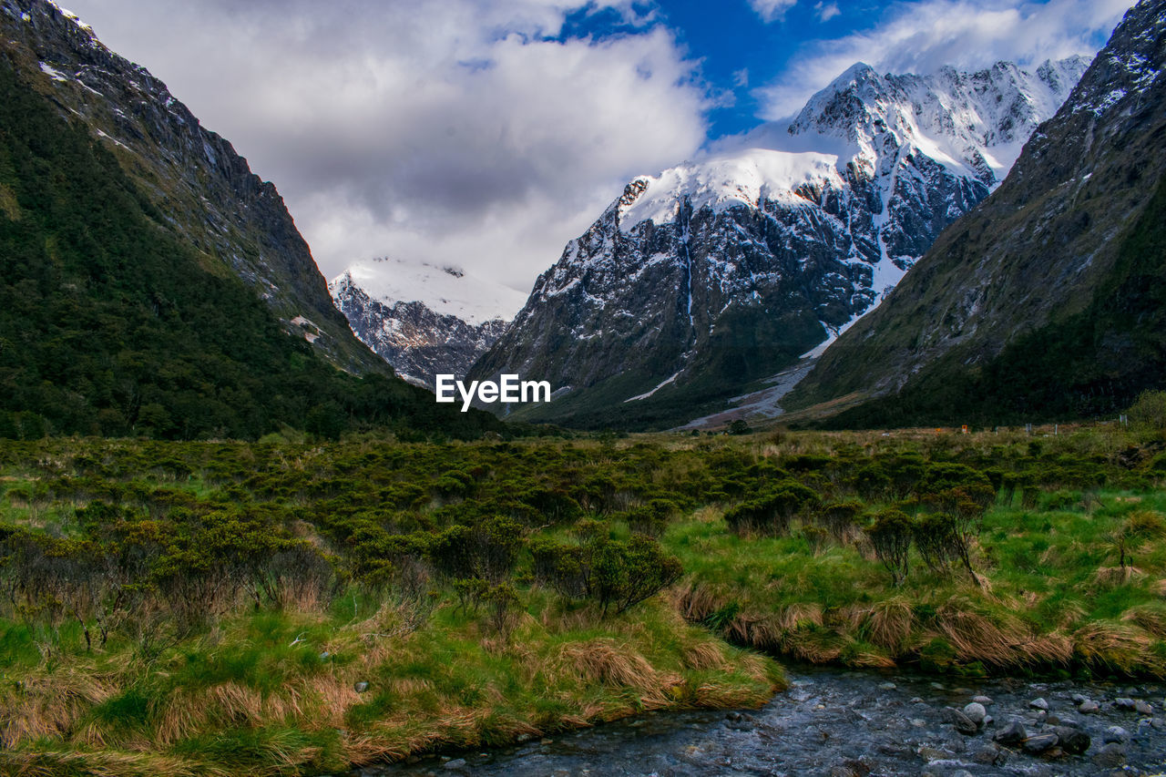 Scenic view of snowcapped mountains and a glacial valley against blue sky with clouds