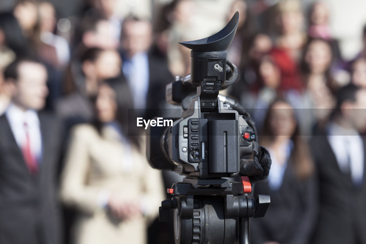 Close-up of camera against people