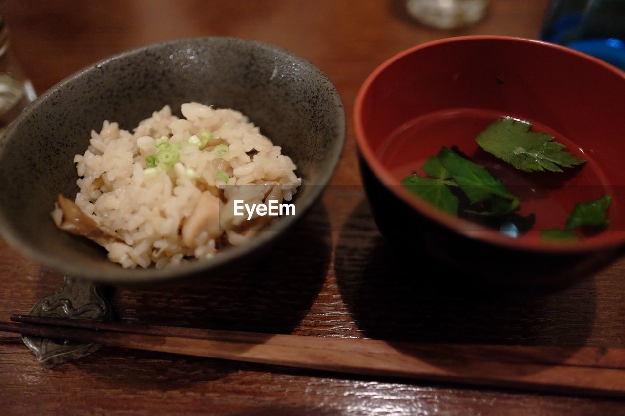 Close-up of food served in bowls by chopsticks on wooden table