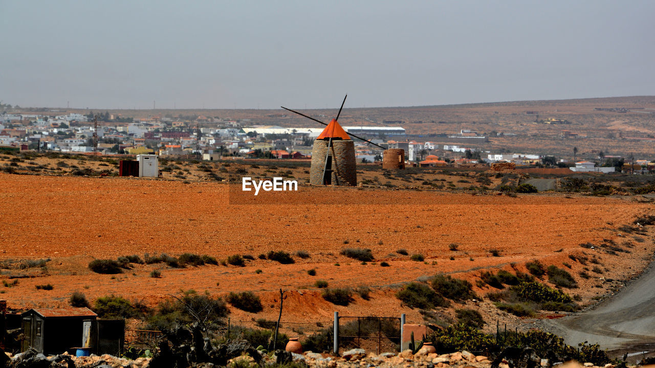 Traditional windmill and buildings in city against sky