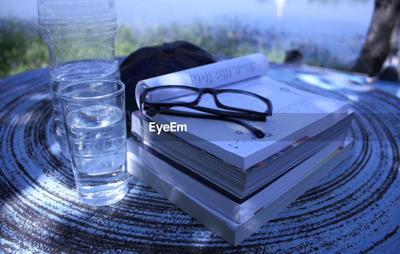 CLOSE-UP OF GLASSES ON TABLE AGAINST GLASS WITH WATER