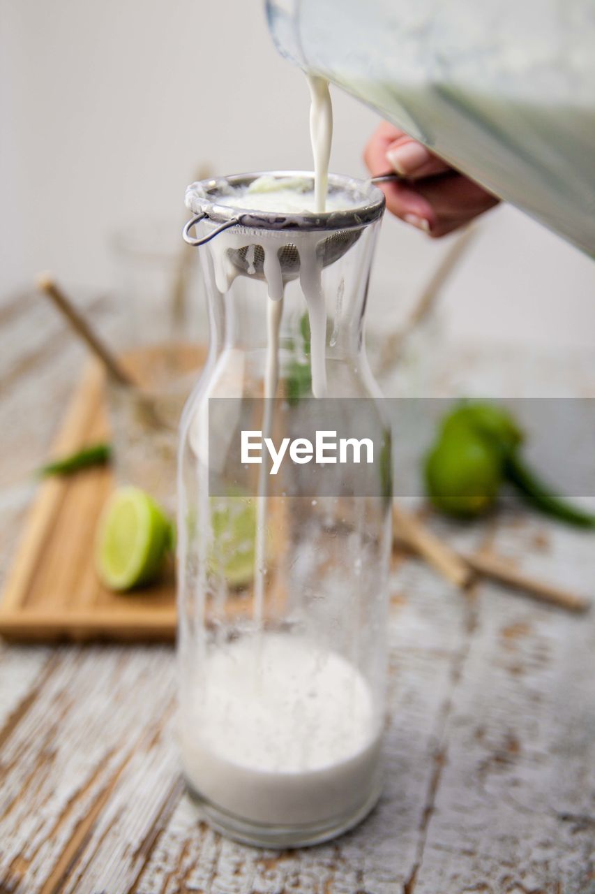 Cropped image of hand pouring drink into glass jar