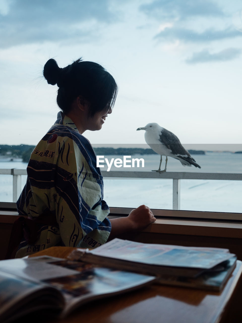 Woman sitting by seagull