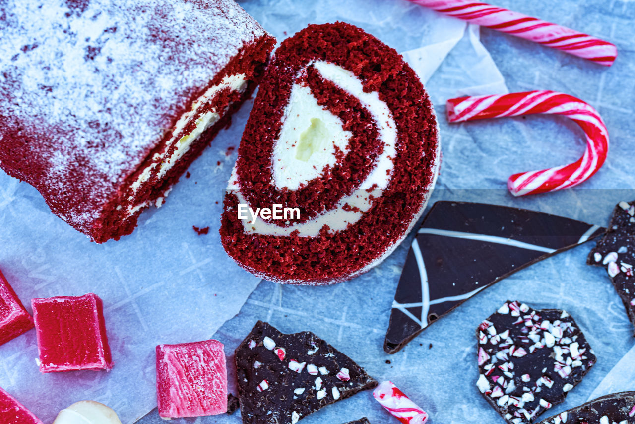 Above view of red velvet cake roll slice amid christmas candies