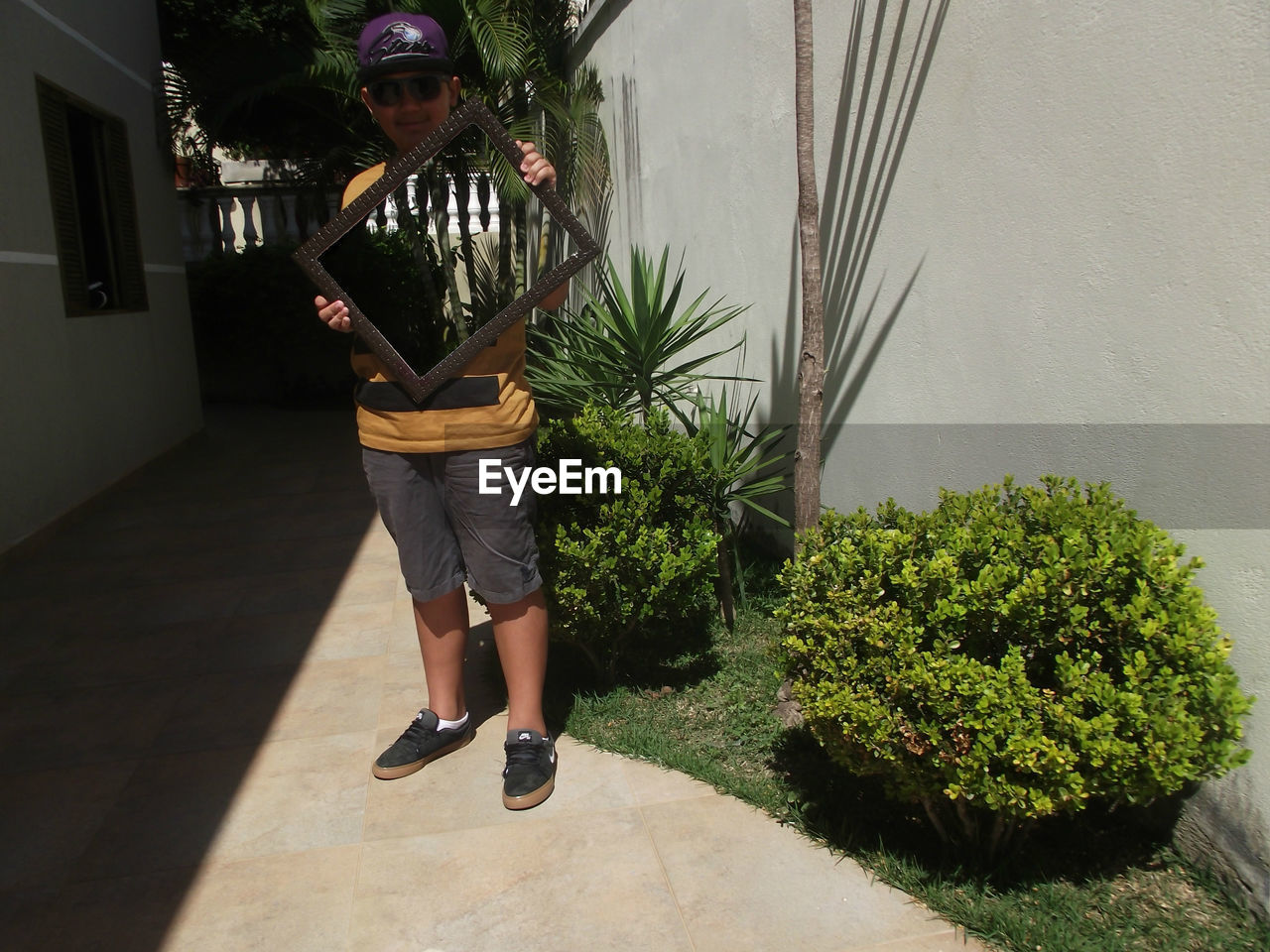 Portrait of boy holding mirror with reflection of trees and railing