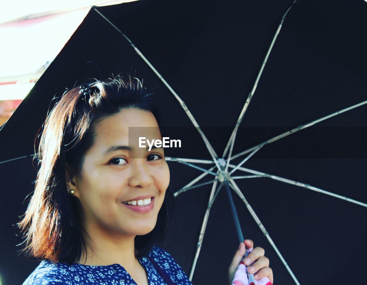 Portrait of happy woman holding umbrella