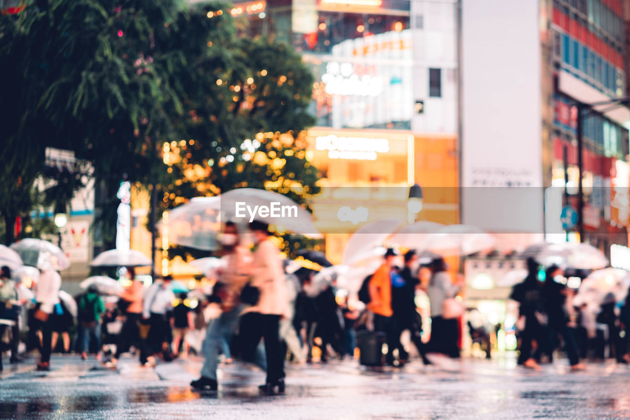 PEOPLE WALKING ON WET STREET IN CITY