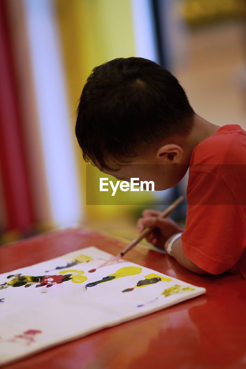 Side view of boy making drawing on table