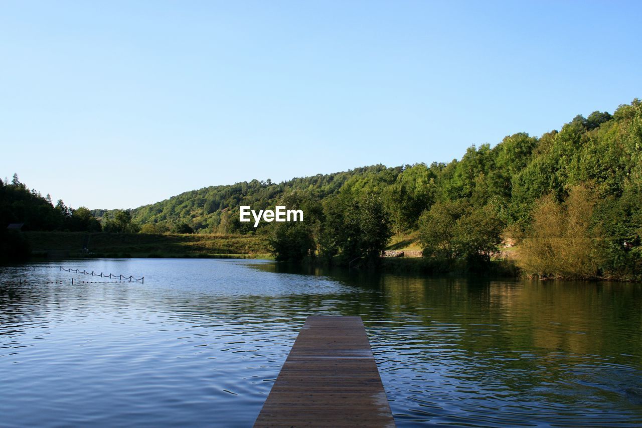 Scenic view of calm lake against clear blue sky