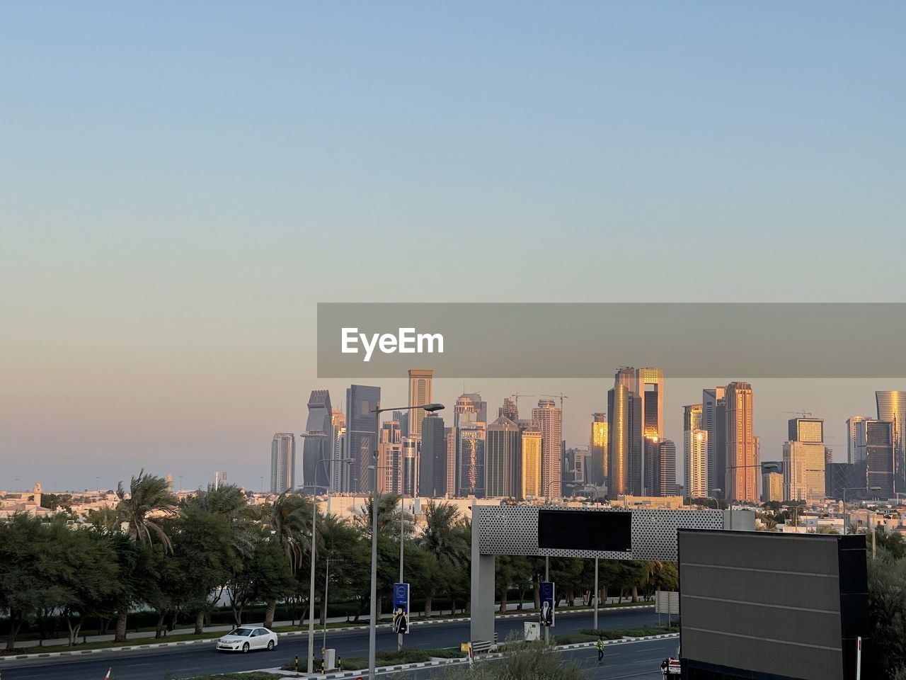 architecture, city, skyline, building exterior, built structure, sky, office building exterior, skyscraper, building, urban skyline, landscape, downtown, cityscape, metropolitan area, horizon, urban area, tower block, nature, sunset, office, city life, transportation, residential district, travel destinations, landmark, downtown district, clear sky, road, no people, street, outdoors, business, travel, metropolis, dusk, copy space, business finance and industry, tree, tower, blue, mode of transportation