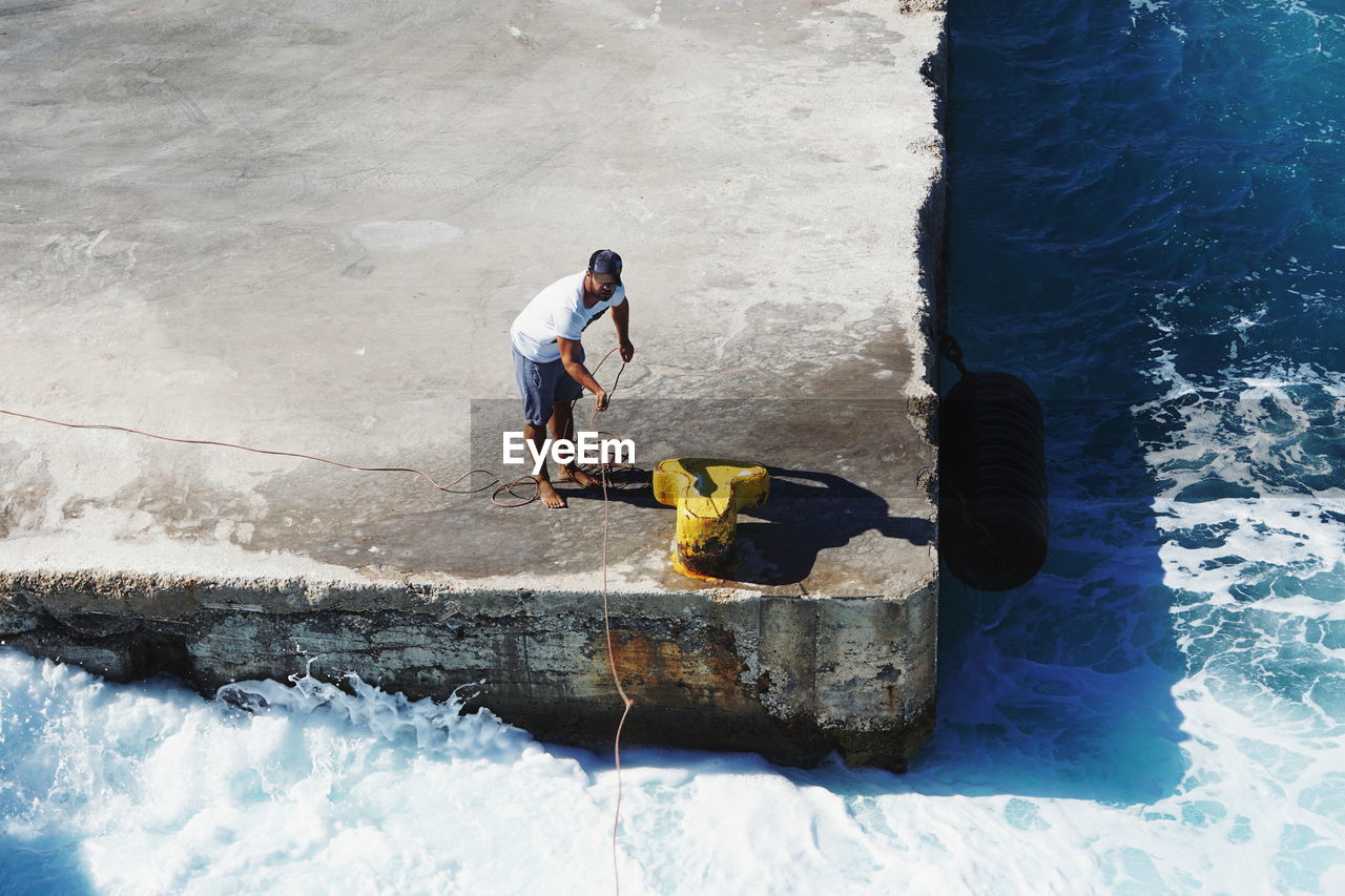 FULL LENGTH OF MAN WITH SEA IN BACKGROUND