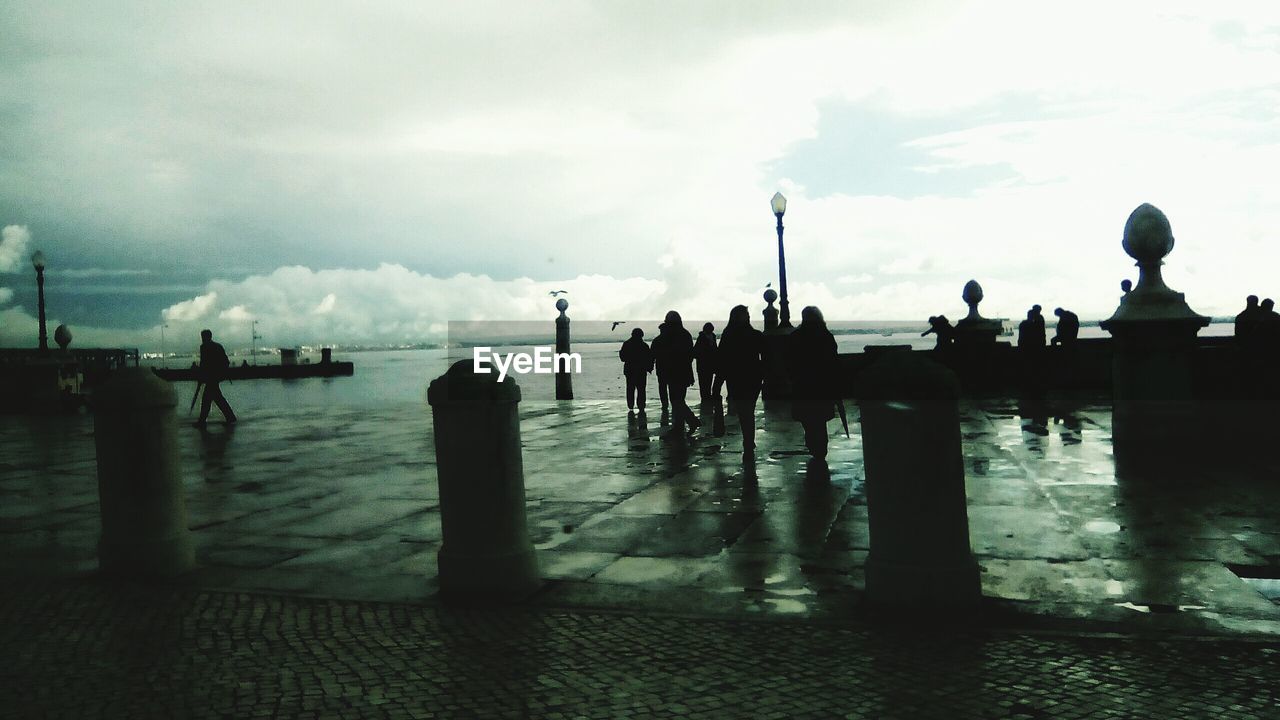 Silhouette people on promenade against sky