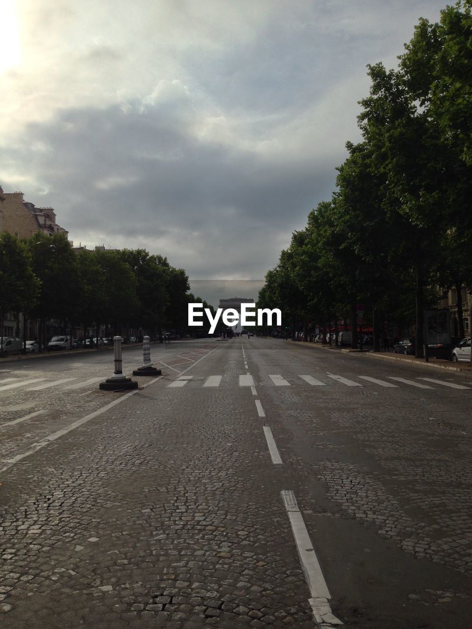 Road leading towards arc de triomphe against cloudy sky in city