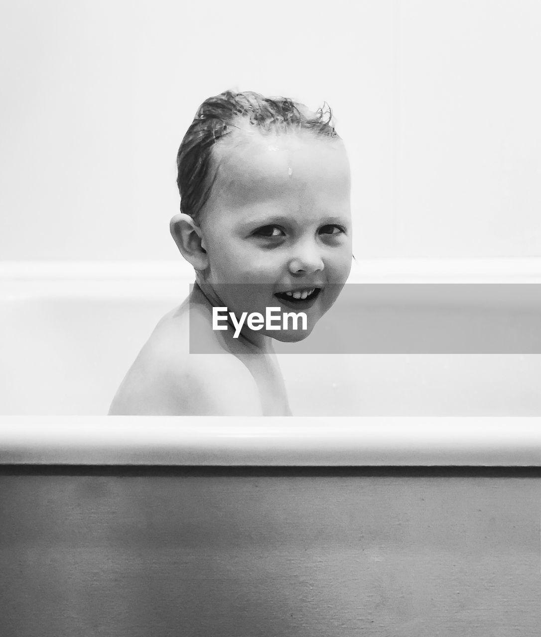 Side view portrait of smiling boy bathing in bathtub at home