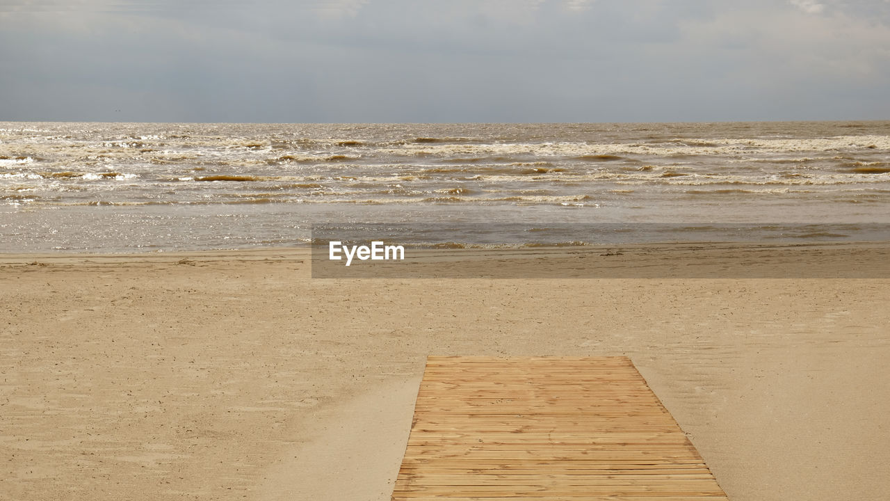 land, beach, sea, water, sky, sand, shore, nature, cloud, scenics - nature, beauty in nature, horizon, coast, horizon over water, tranquility, wood, day, tranquil scene, body of water, ocean, natural environment, no people, outdoors, wave, non-urban scene, idyllic