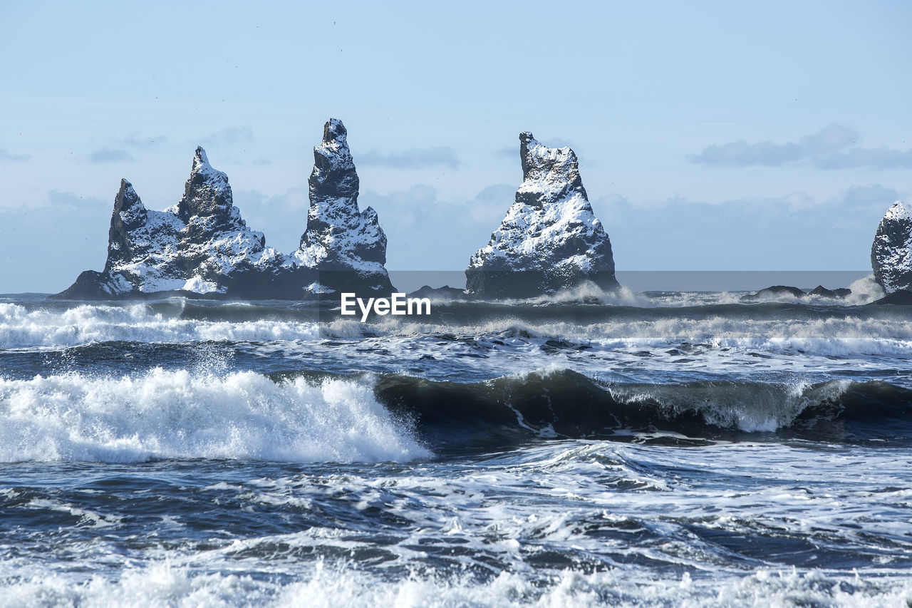 Three pinnacles of vik with rough waves, south iceland in wintertime
