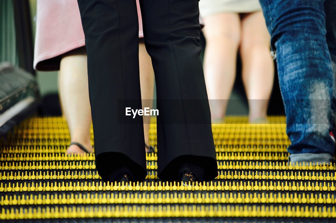 Low section of people standing on escalator