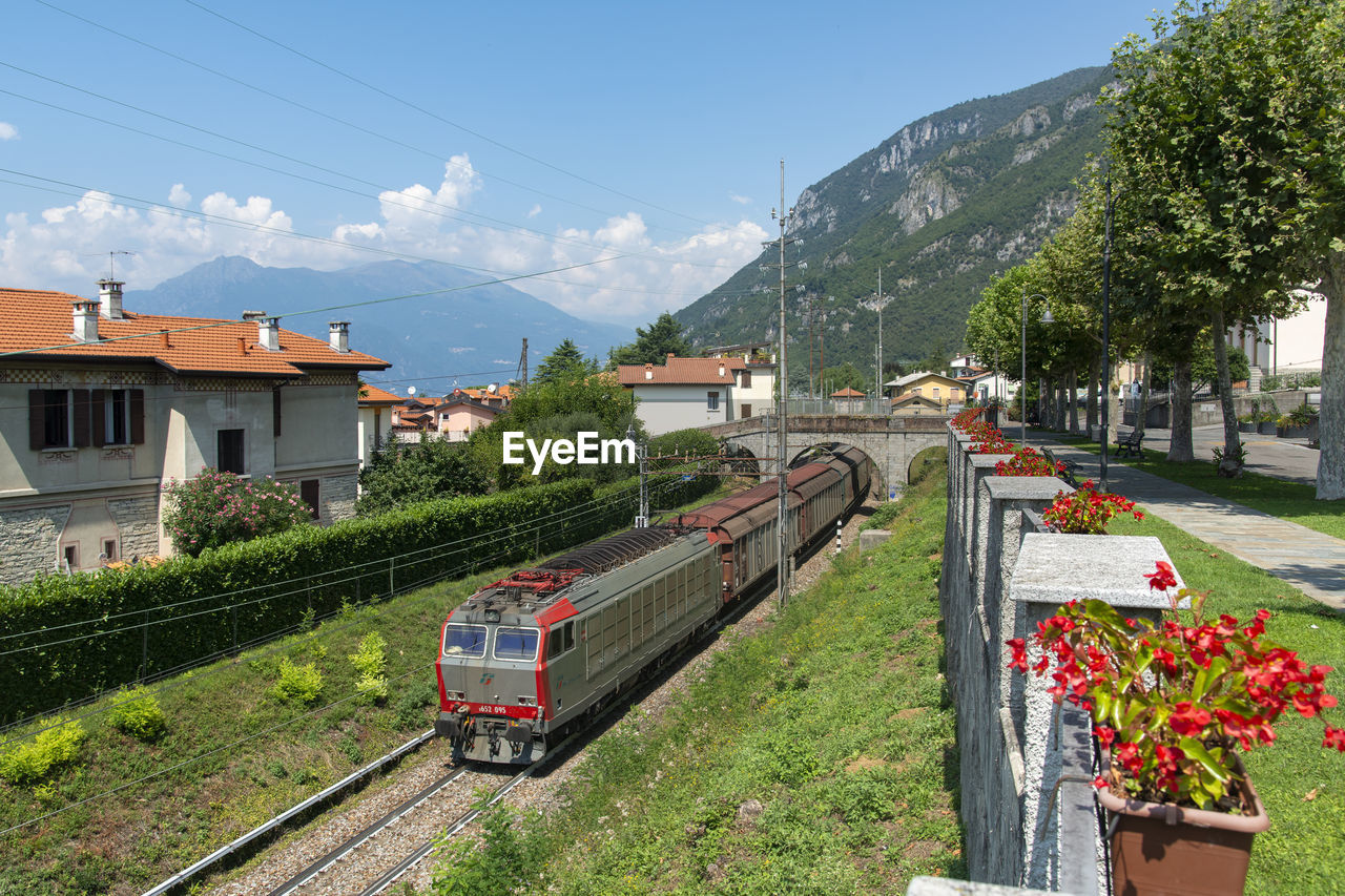 TRAIN ON RAILROAD TRACKS BY CITY AGAINST SKY