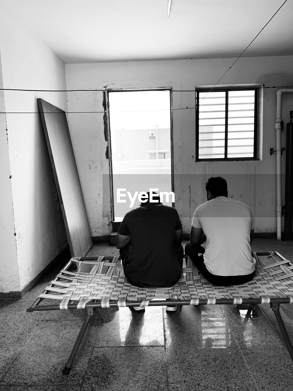 REAR VIEW OF MAN SITTING ON SEAT IN CORRIDOR