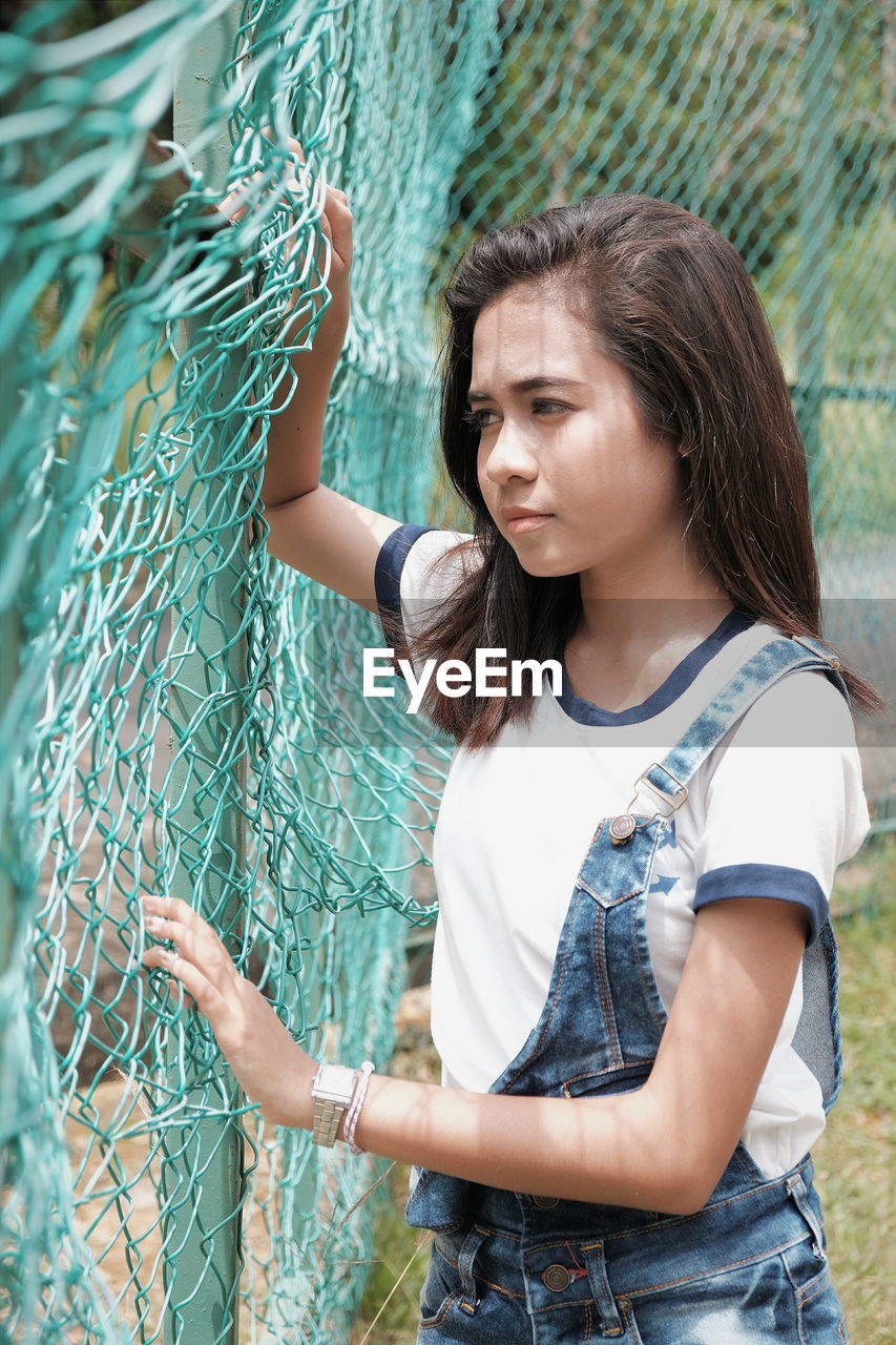 Young woman standing by nets