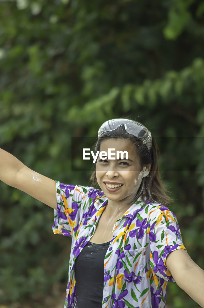 Portrait of smiling woman standing against trees