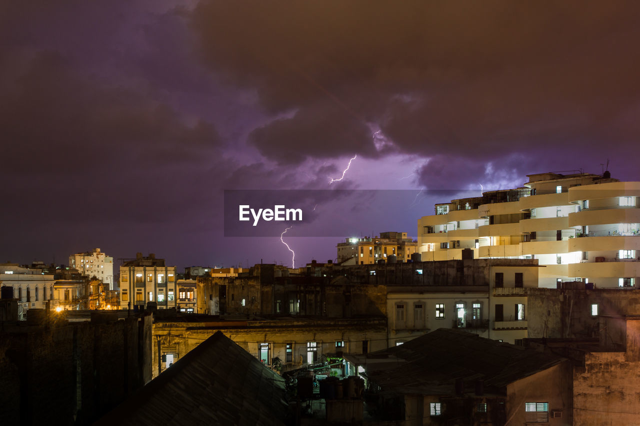 Illuminated buildings against cloudy sky