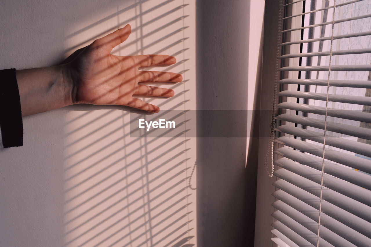 Close-up of hand on wall by window