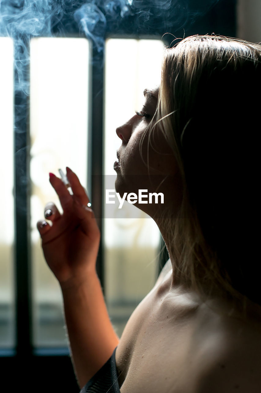 A girl smokes cigarette on black background