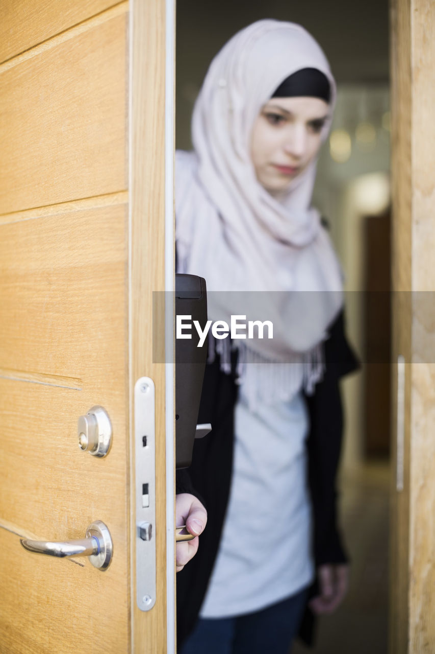 Young muslim woman closing front door