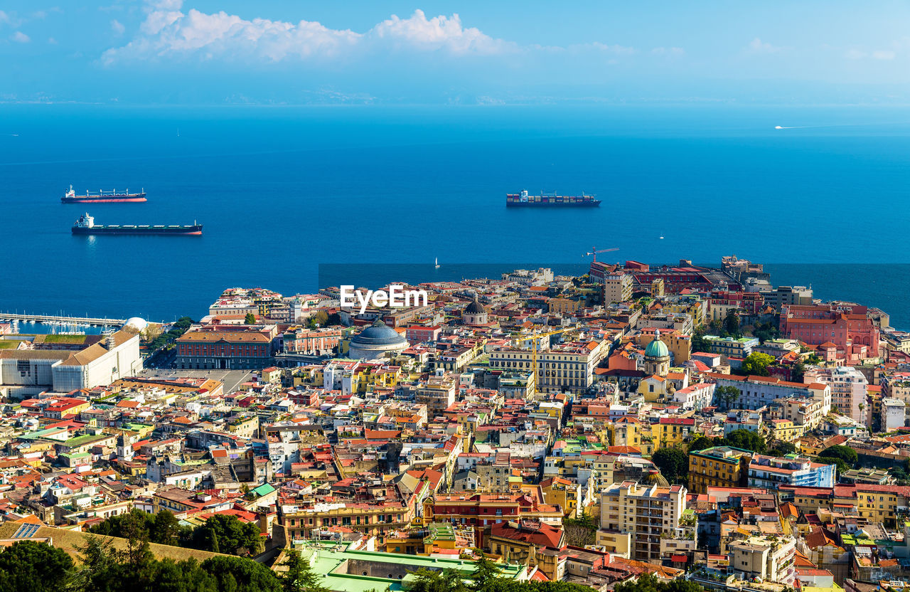 AERIAL VIEW OF SEA AND BUILDINGS IN CITY