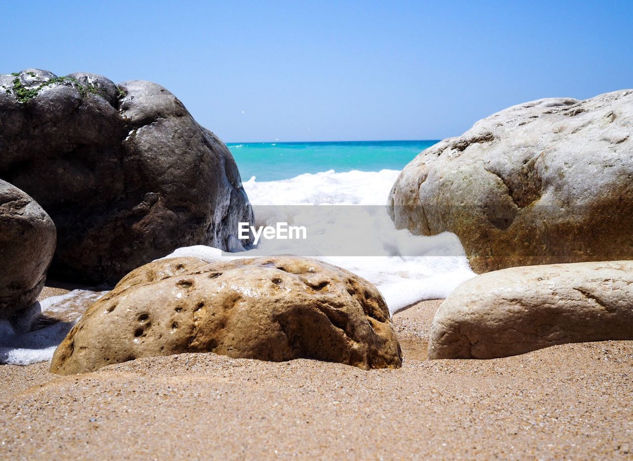 Rocks on beach against clear sky