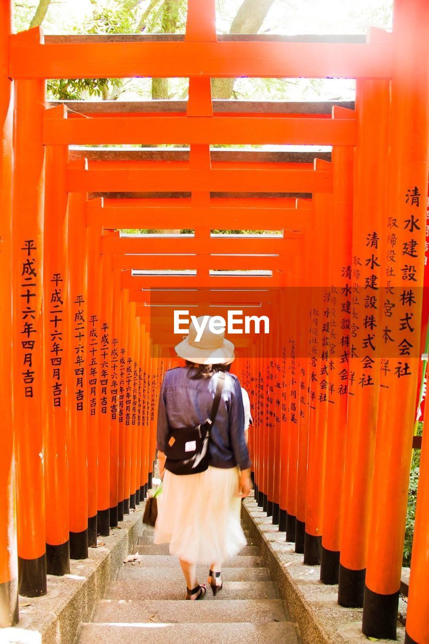 Rear view of woman walking through torii gates at hie shrine