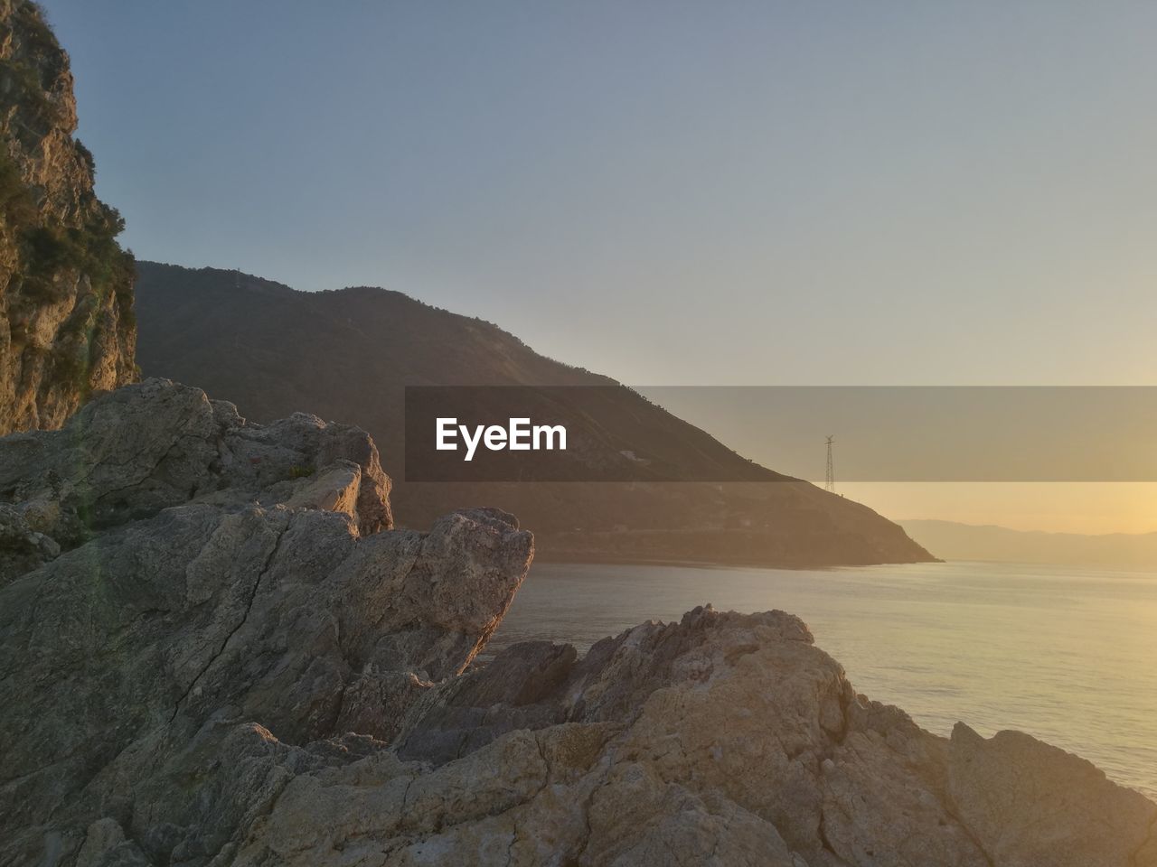 Scenic view of sea and mountains against clear sky