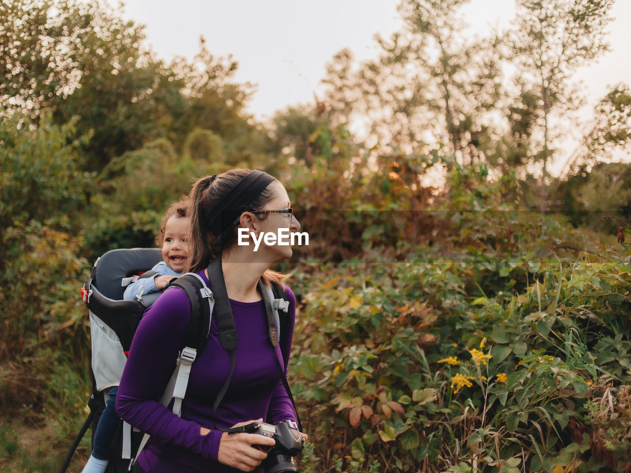 Smiling mother with cute son on back standing on forest