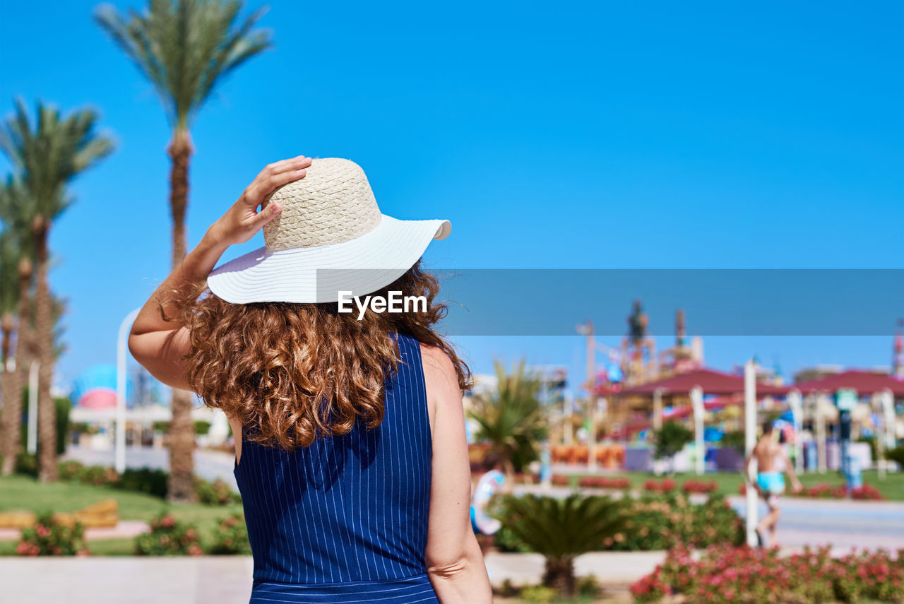 Rear view of woman wearing hat against blue sky