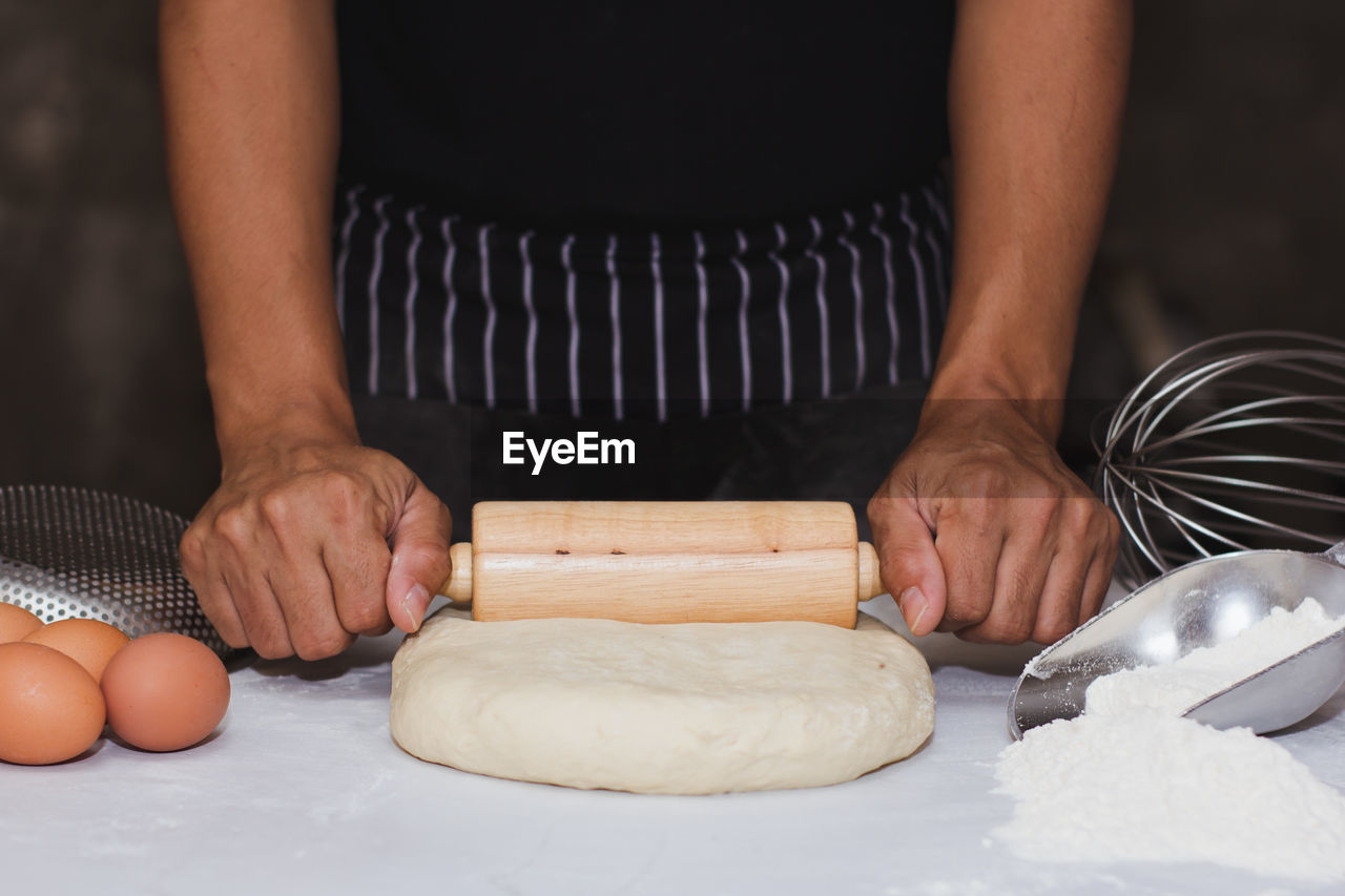 MIDSECTION OF PERSON PREPARING FOOD IN KITCHEN