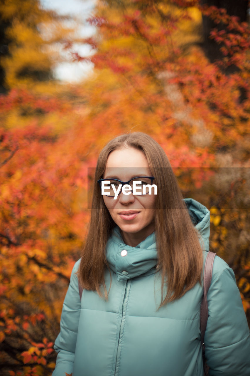 Portrait of beautiful woman standing against trees during autumn