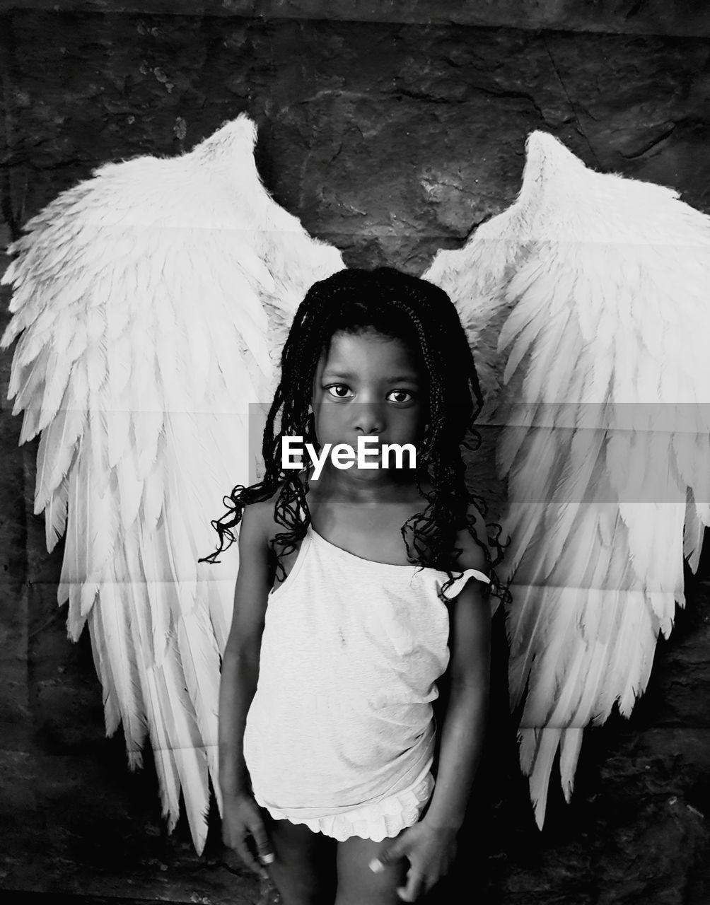 Portrait of girl standing against wall with wings